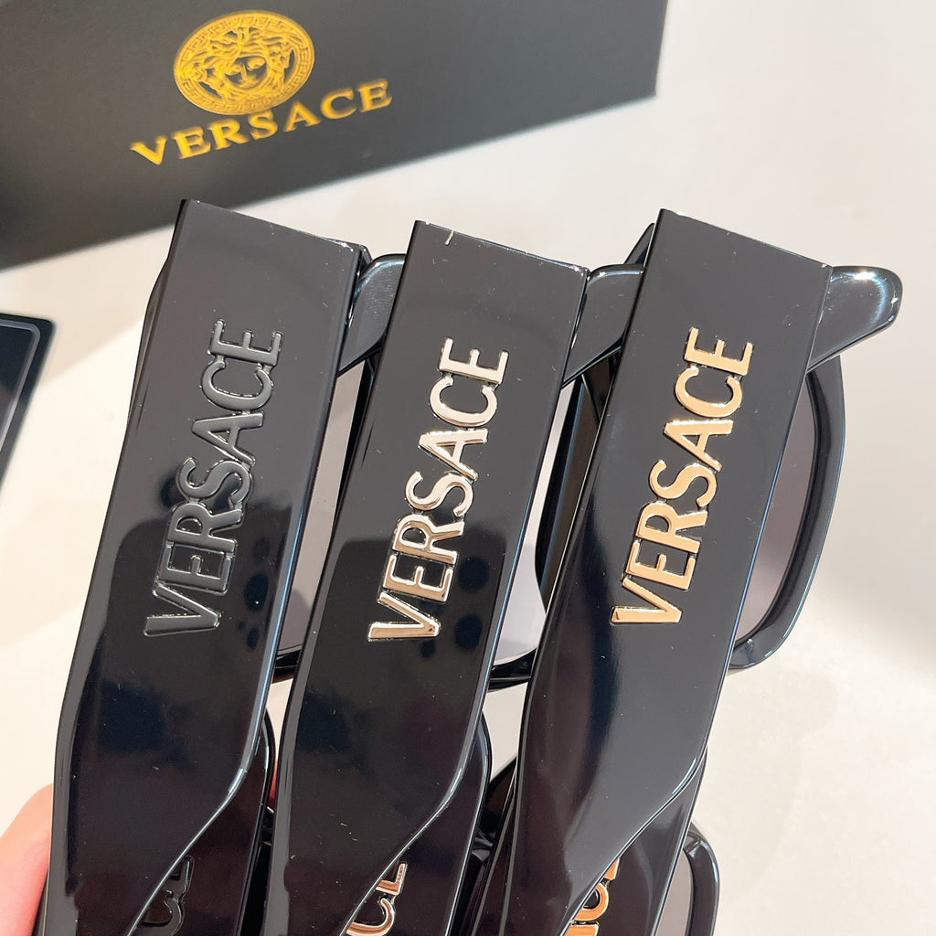 Close-up of black eyeglass frames showing VERSACE text on temple arms