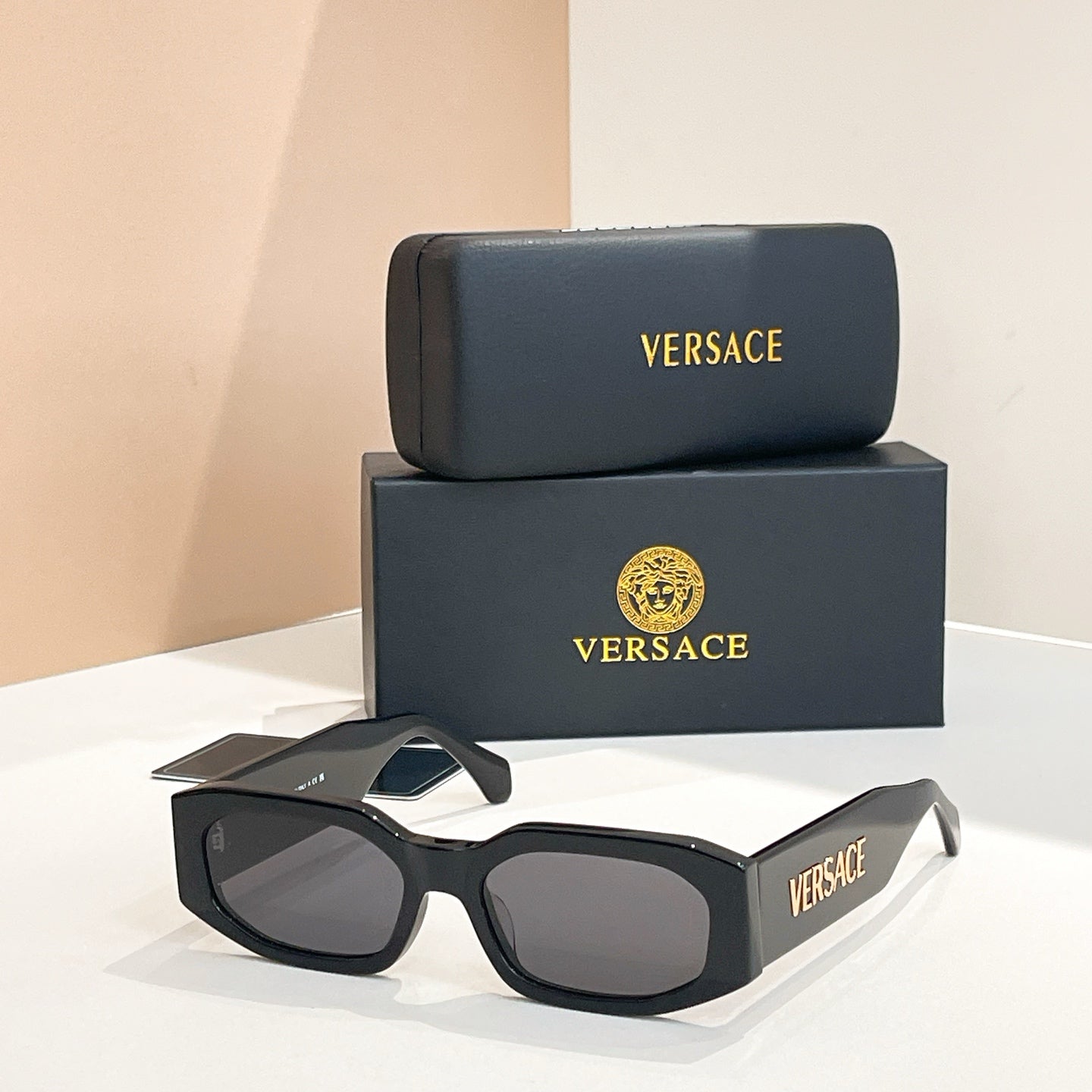 Black acetate sunglasses with dark lenses and VERSACE logo on the temples