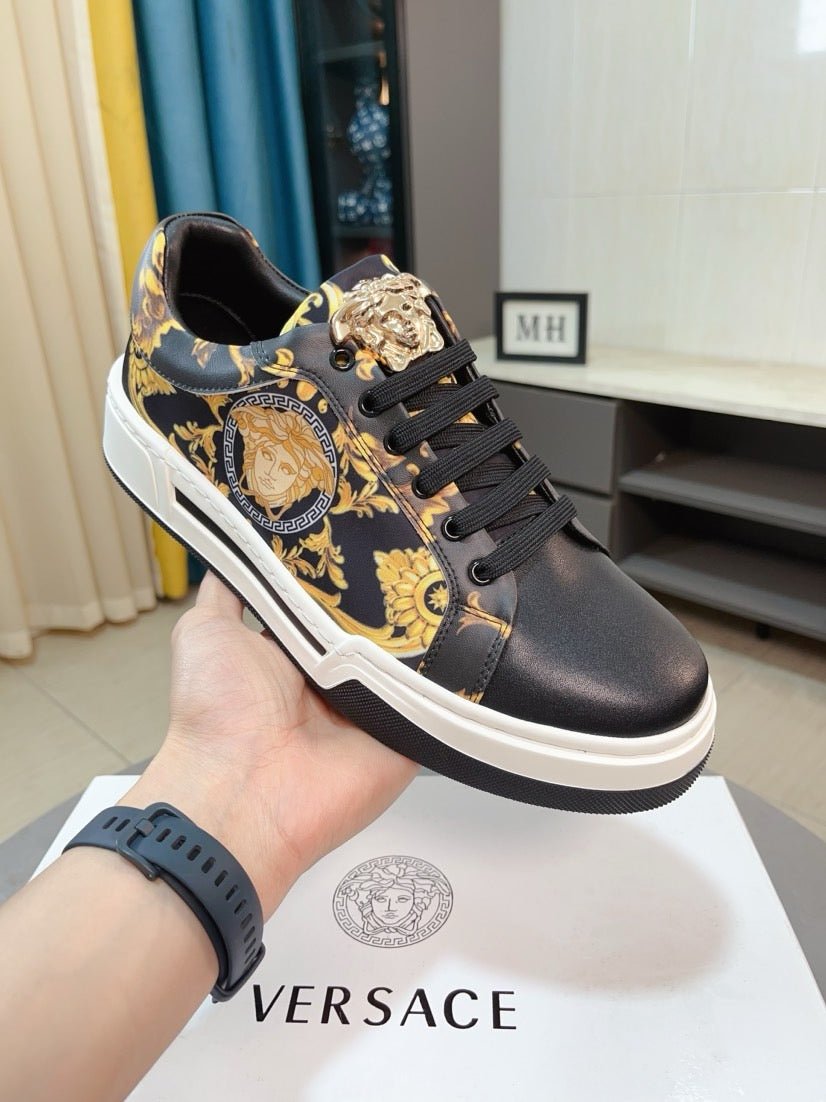 Versace sneakers held in hand, dark leather with gold baroque motifs and black laces