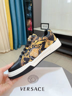 Versace sneakers held near box, dark upper with gold baroque pattern and black laces
