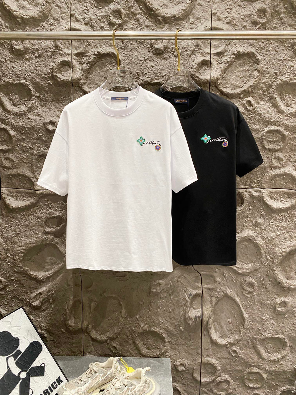 White and black T-shirts on hangers with small chest embroidery
