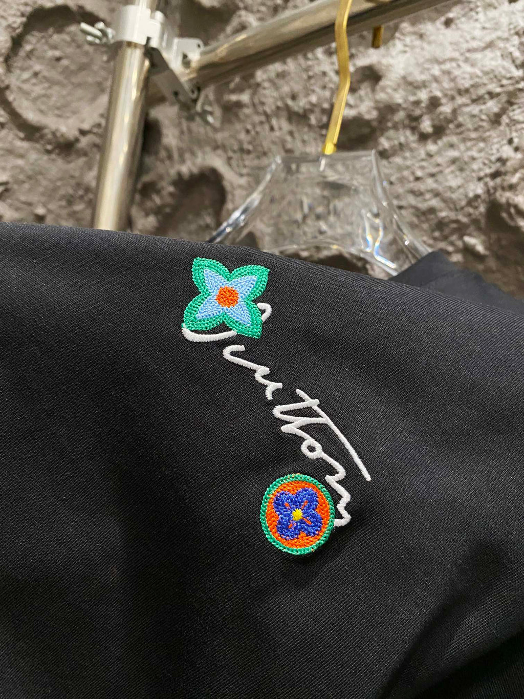 Black T-shirt embroidery detail with green flower and crest patches