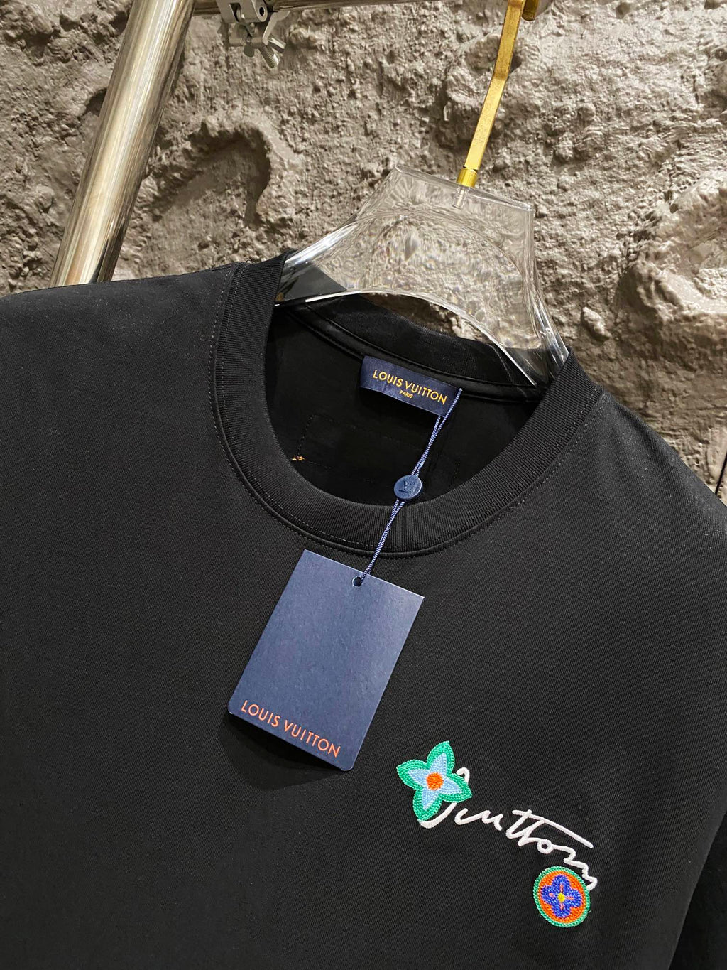 Black T-shirt neckline with embroidered logo patch and Louis Vuitton tag
