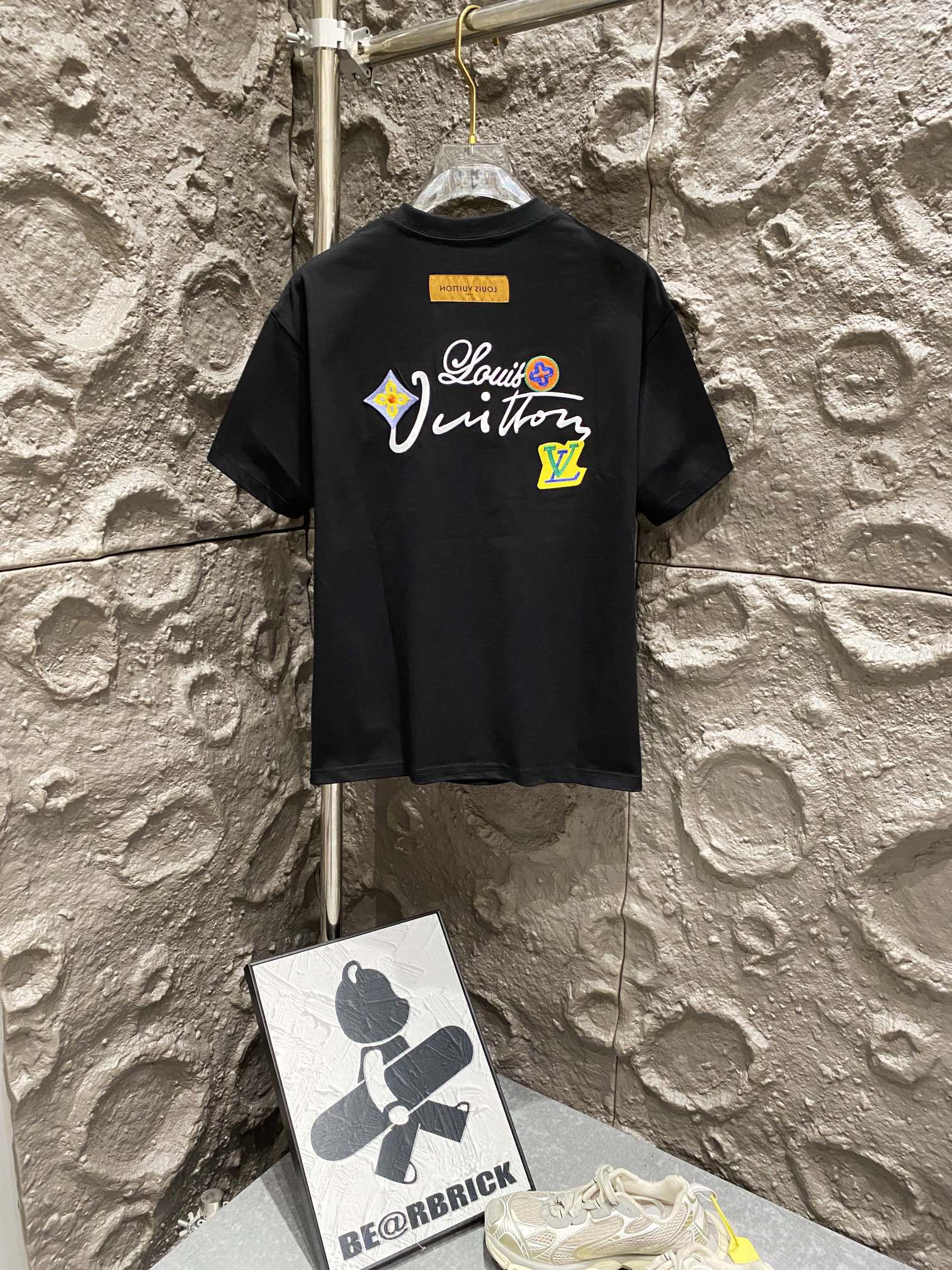 Black T-shirt back with large script graphic and logo patch