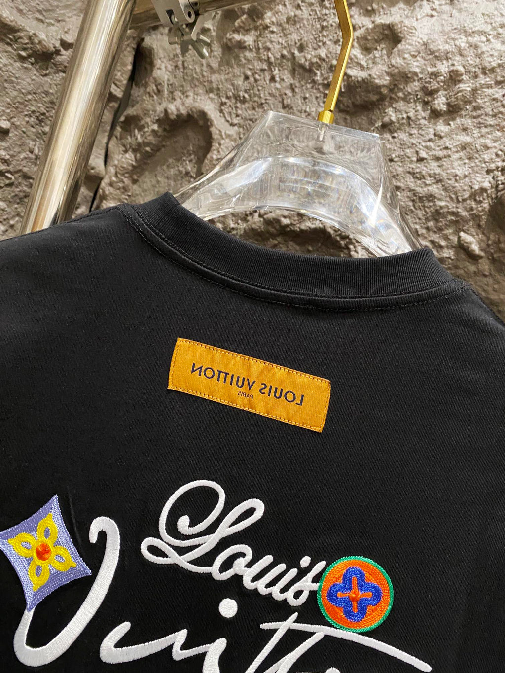 Black T-shirt front with colorful logo embroidery and yellow neck tag