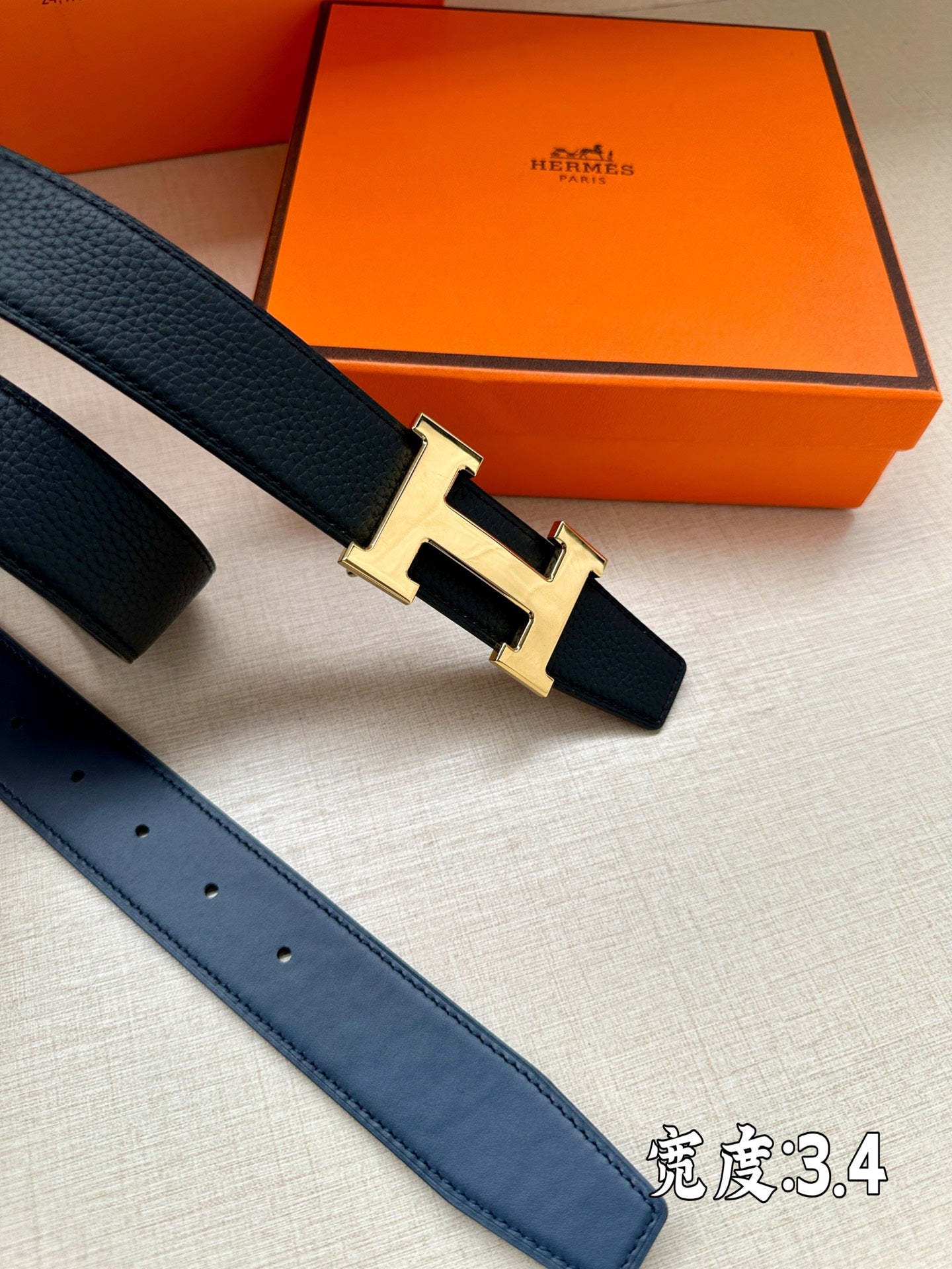 Dark blue leather belt with silver H buckle detail and punched strap holes