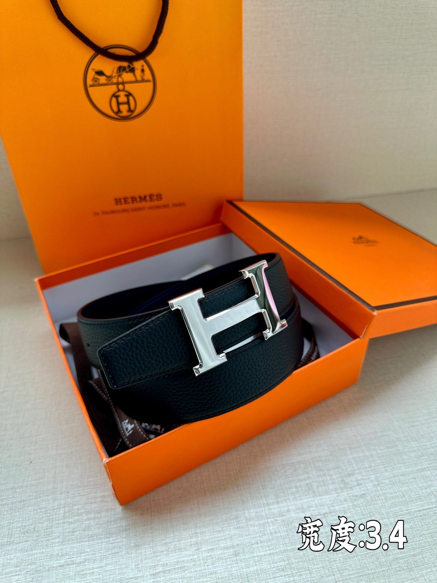 Dark blue leather belt with silver buckle resting inside an open box
