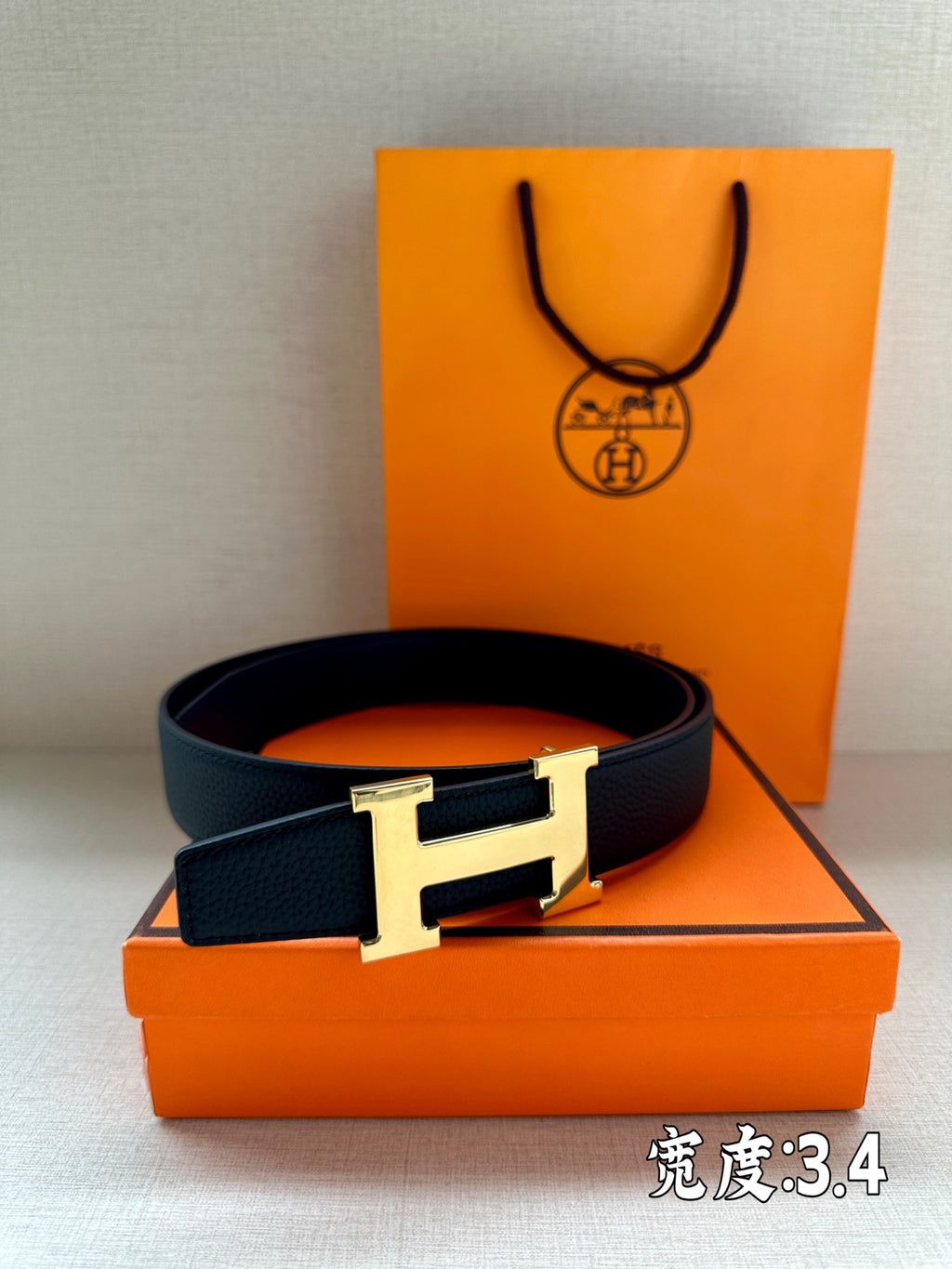 Dark blue leather belt with silver buckle displayed beside an orange box