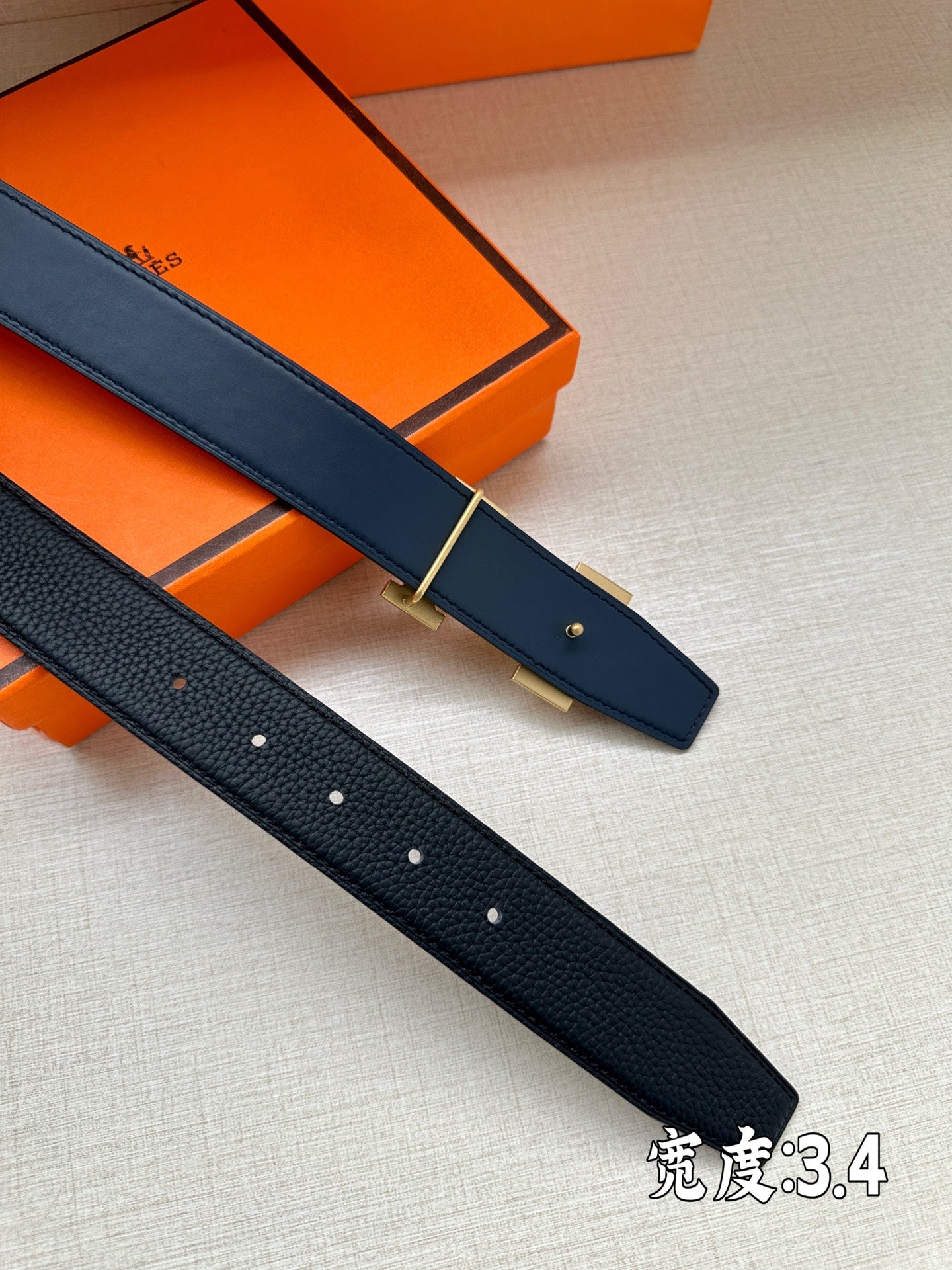 Two dark blue leather belt straps with silver buckles and punch holes