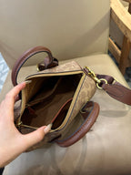 Coah bag interior view with open top zipper, tan logo lining, and brown leather trim