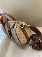 Coah crossbody duffle bag in tan logo canvas with brown leather trim and gold hardware accents
