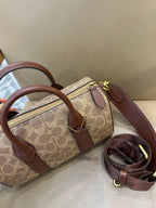 Coah small top-handle bag showing zipper pocket, tan logo canvas, brown leather trim, and chain pulls