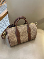 Coah tan logo canvas satchel with brown leather top handles, zip closure, and gold hardware