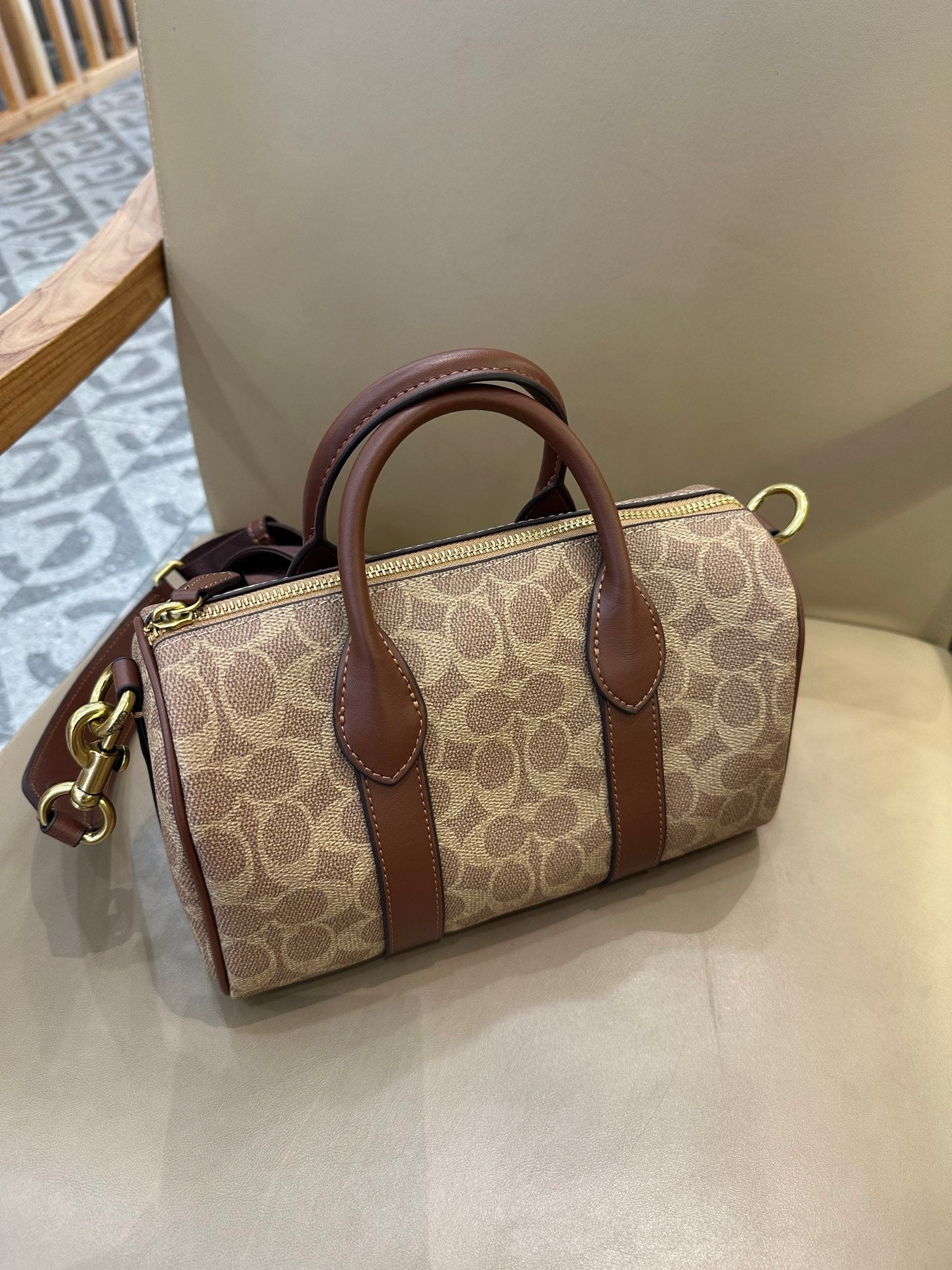 Coah tan logo canvas satchel with brown leather top handles, zip closure, and gold hardware