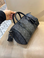 Coah bag with dark patterned fabric, front zip pocket, and top handles