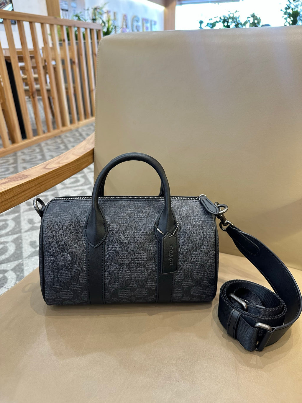 Coah bag with dark patterned exterior, top handles, and detachable crossbody strap