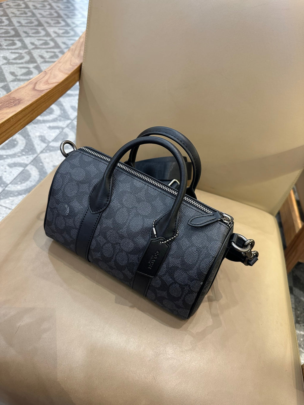 Coah bag with dark patterned exterior, zip front pocket, and crossbody strap