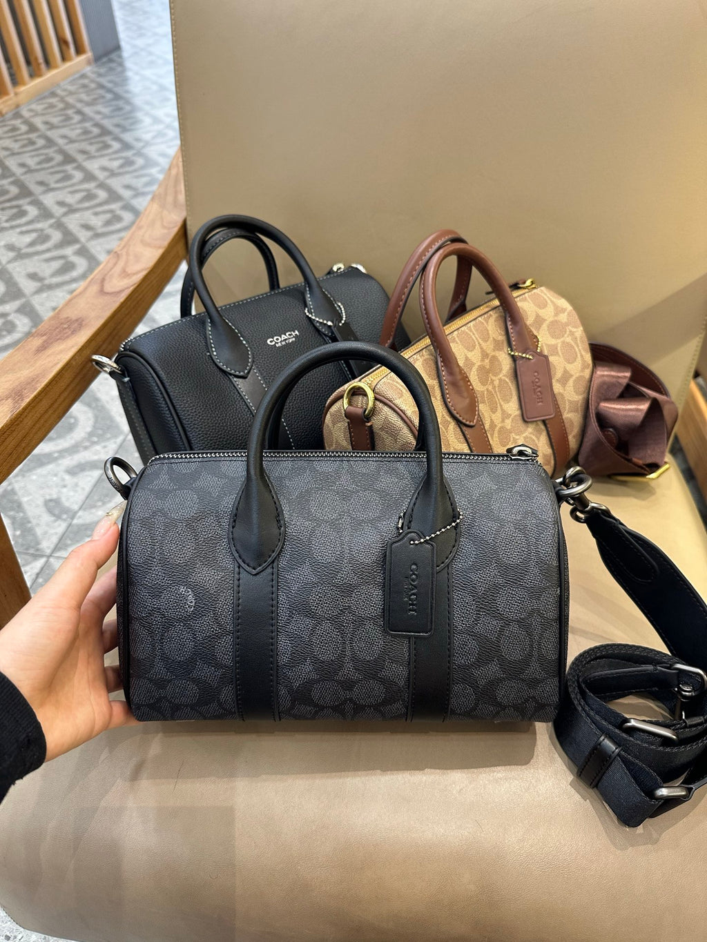 Coah bag with dark patterned exterior, top handles, and detachable crossbody strap
