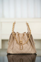 Quilted light beige shoulder bag with chain handles and CC emblem at center front.