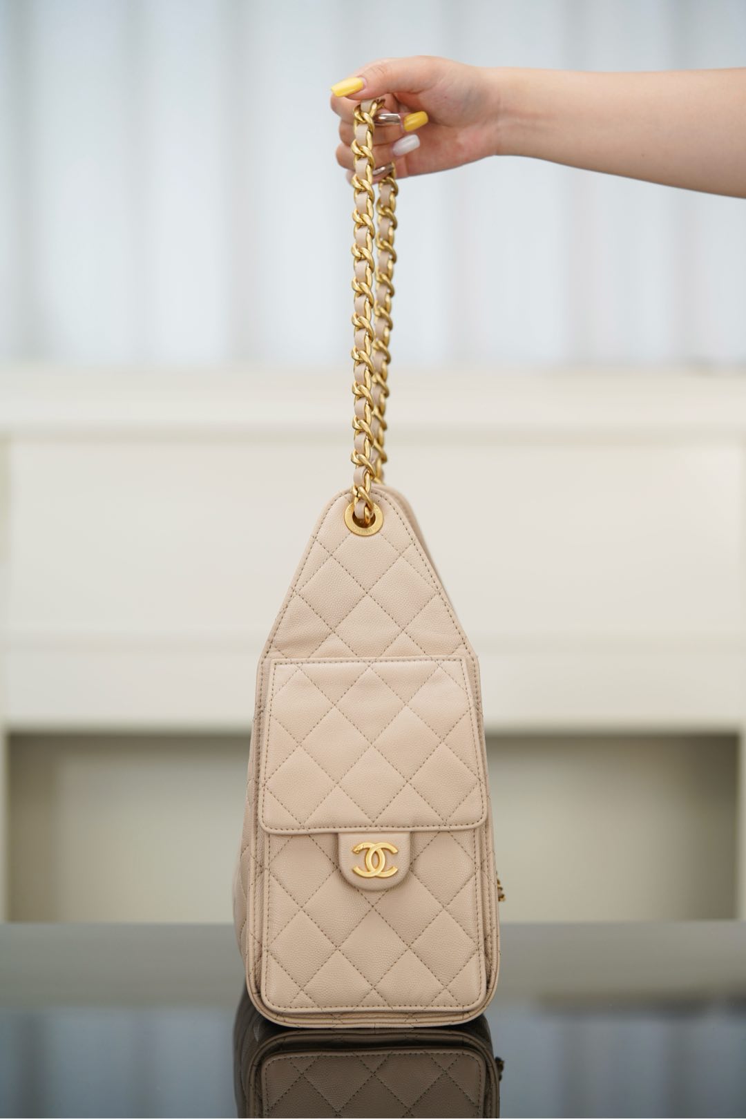 Quilted light beige mini shoulder bag with chain strap and CC logo on front.