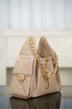 Quilted light beige shoulder bag side view with small flap pocket and chain strap.