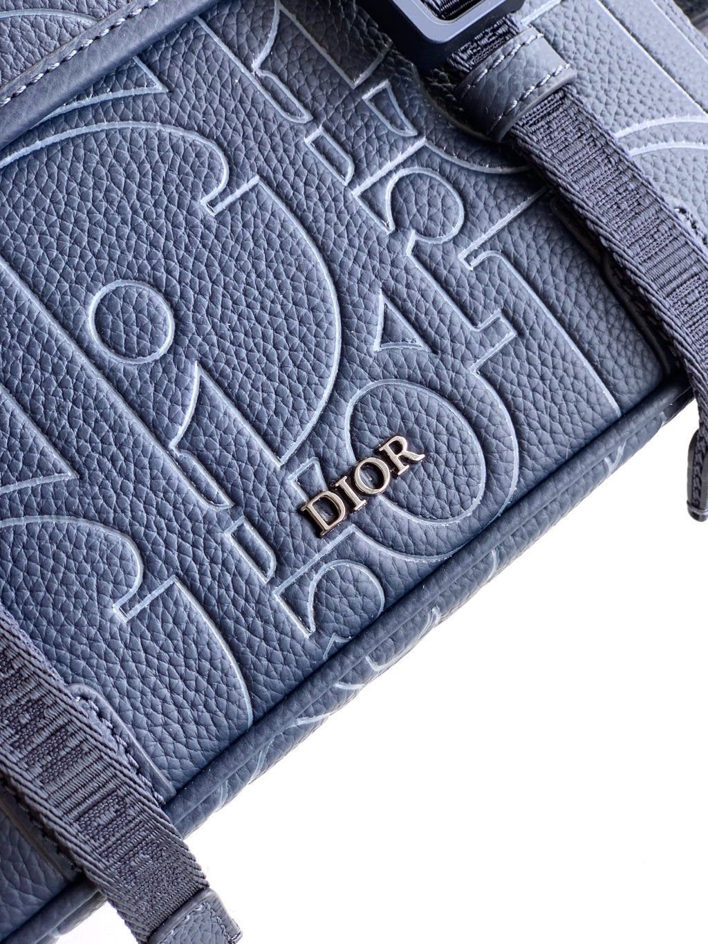 Dior blue textured leather bag close-up with embossed monogram pattern and Dior lettering