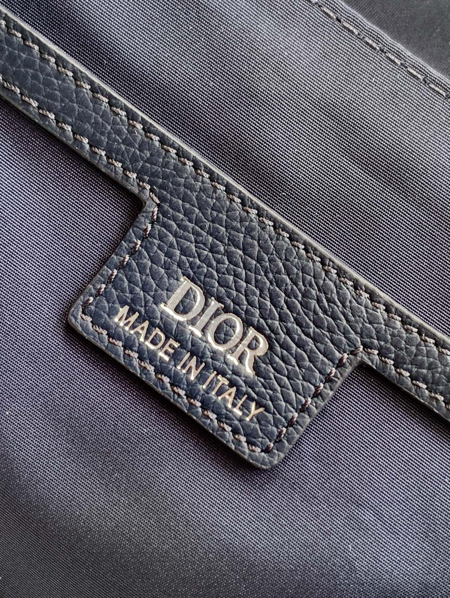 Dior blue leather bag close-up showing “DIOR” logo and “MADE IN ITALY” label