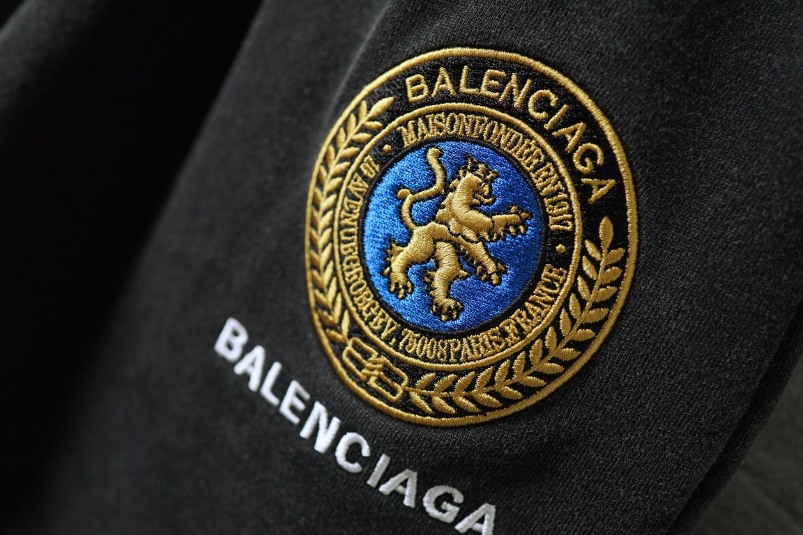 Balenciaga crest emblem with gold trim on dark shorts fabric