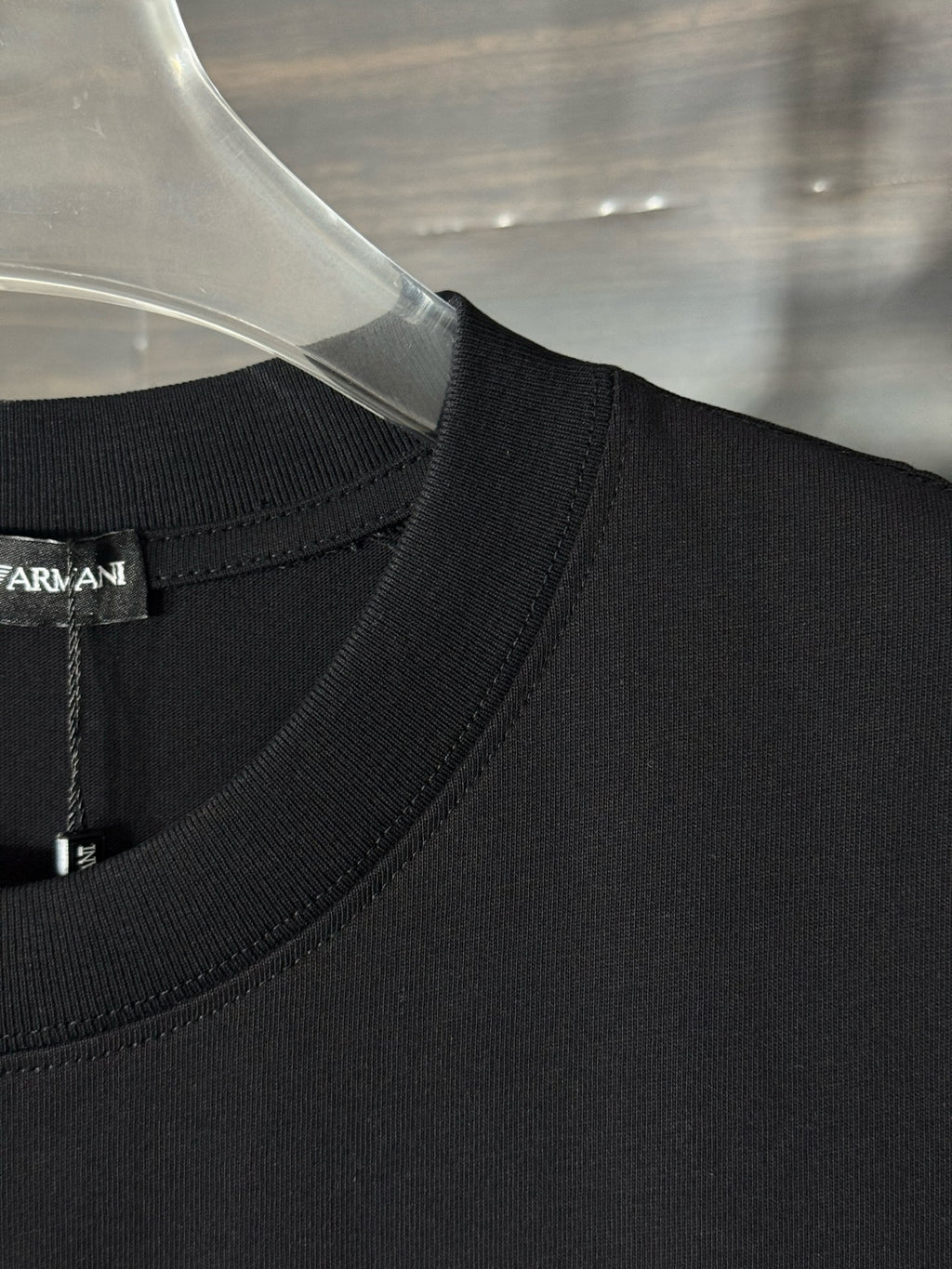 Black crewneck T-shirt neckline and shoulder seam detail.