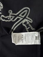 Black T-shirt with rhinestone script logo and white size label attached.