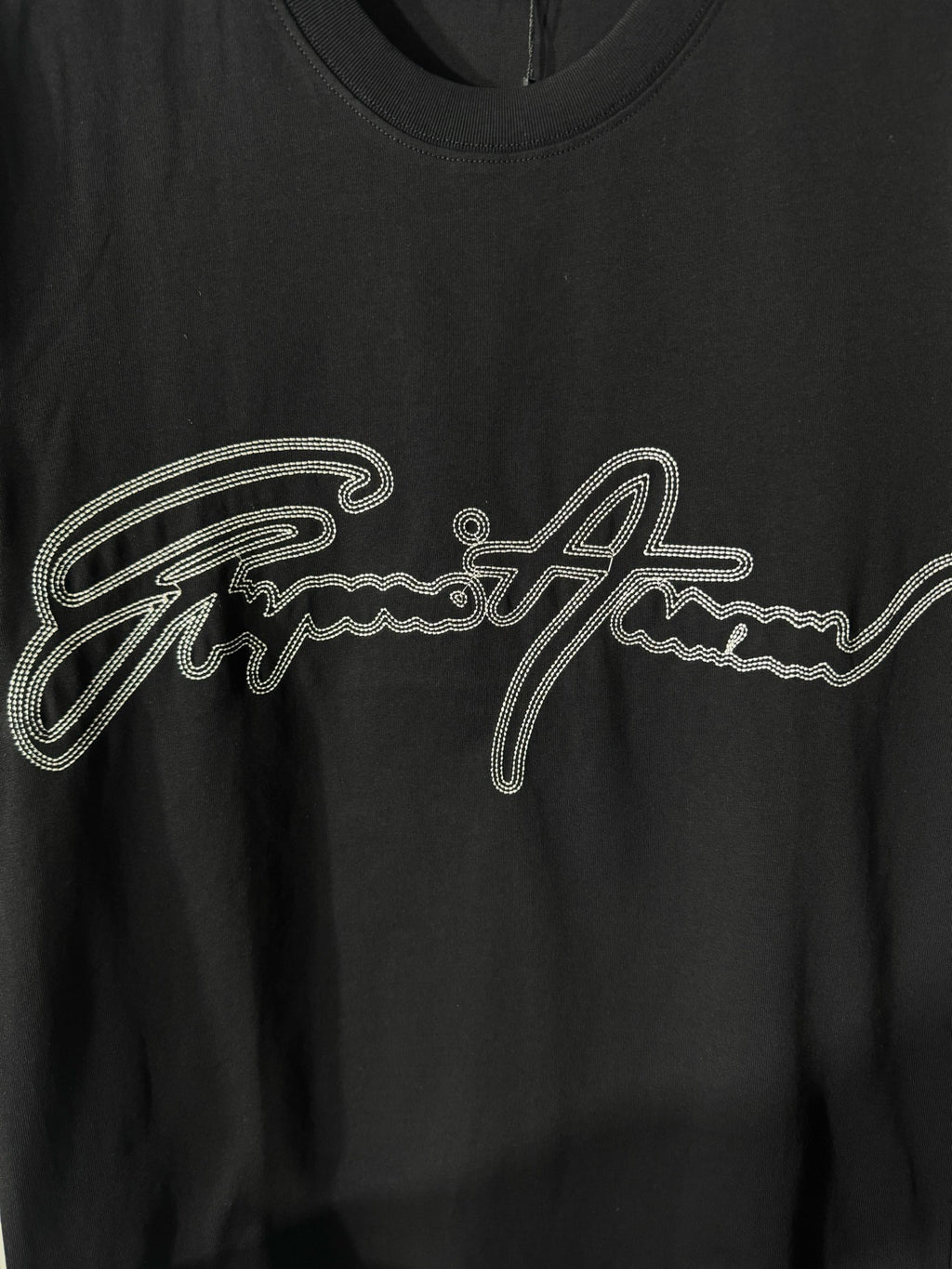 Black crewneck T-shirt with rhinestone script logo detail on the chest.