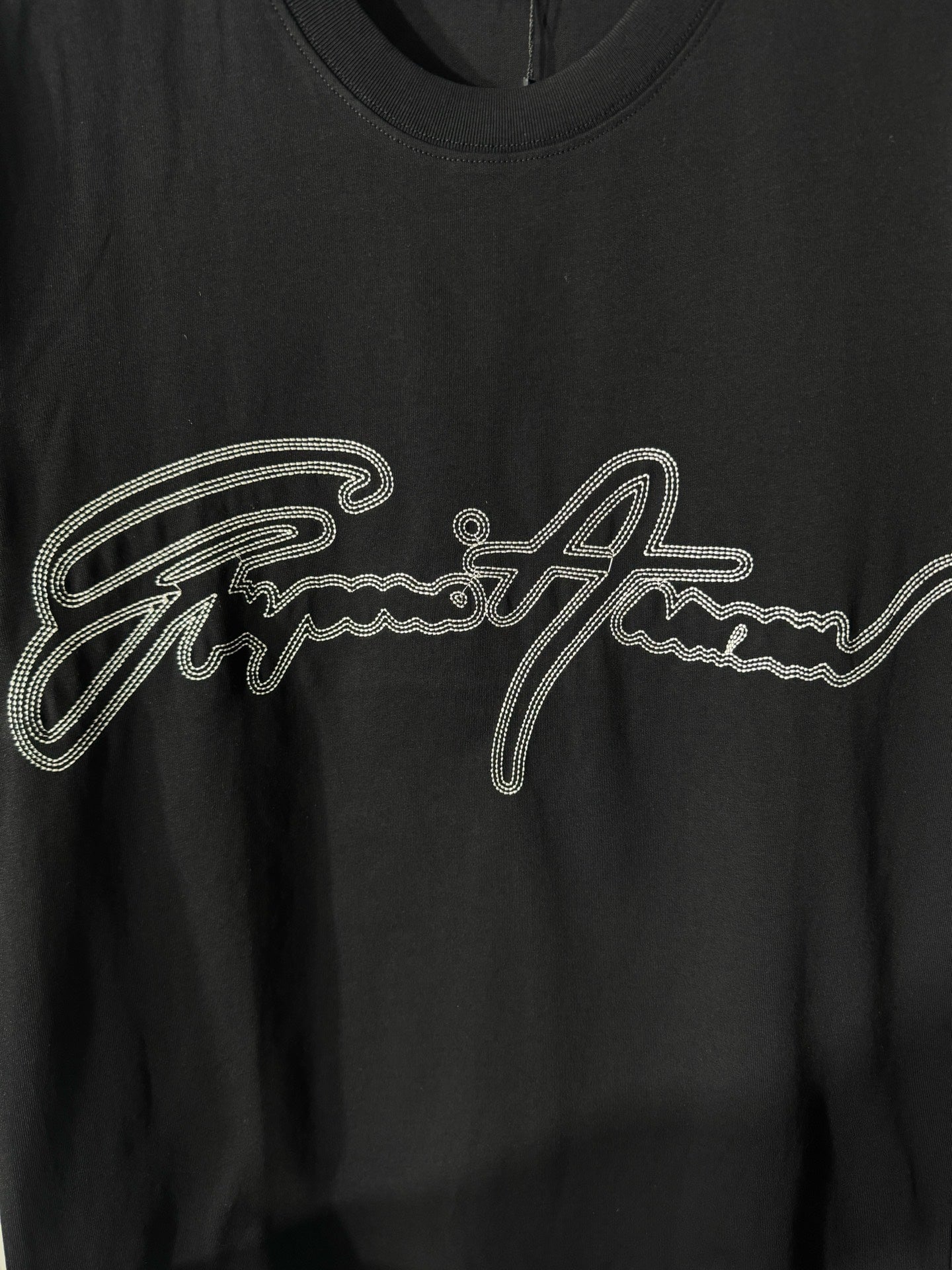 Black crewneck T-shirt with rhinestone script logo detail on the chest.
