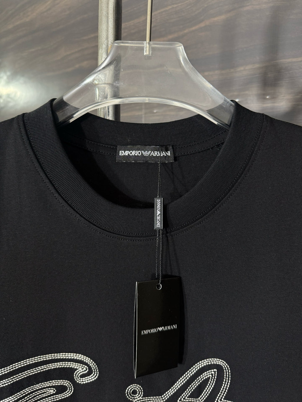 Black crewneck T-shirt with Emporio Armani label and hanging tag at neckline.
