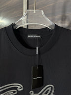 Black crewneck T-shirt with Emporio Armani label and hanging tag at neckline.