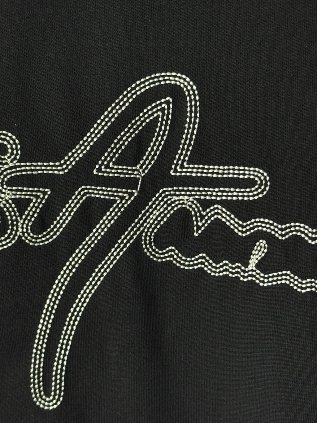 Black T-shirt with large rhinestone script graphic across the front.
