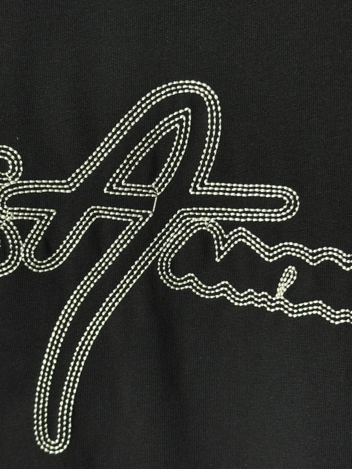 Black T-shirt with large rhinestone script graphic across the front.