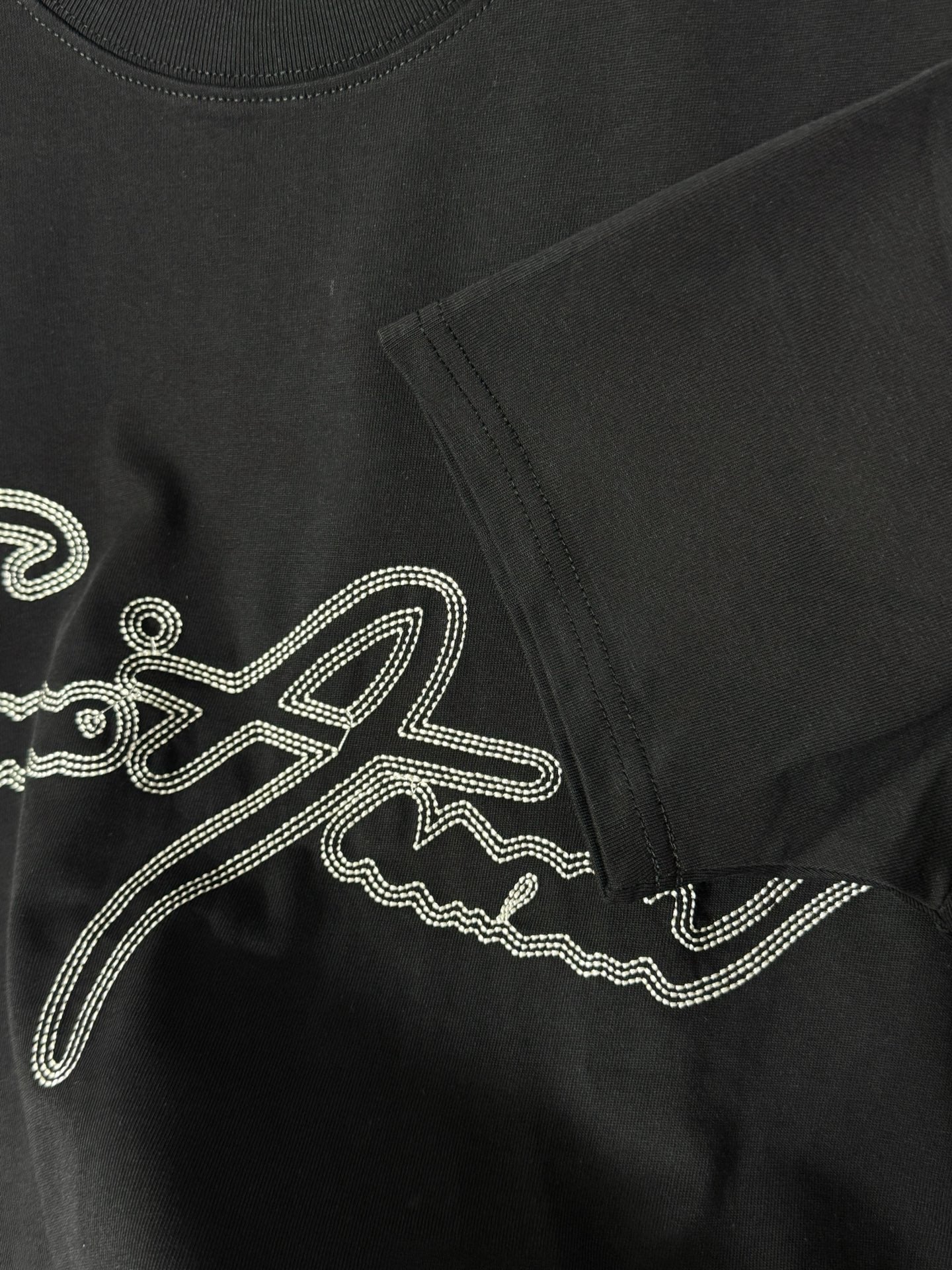 Black T-shirt with rhinestone script logo and side seam detail.