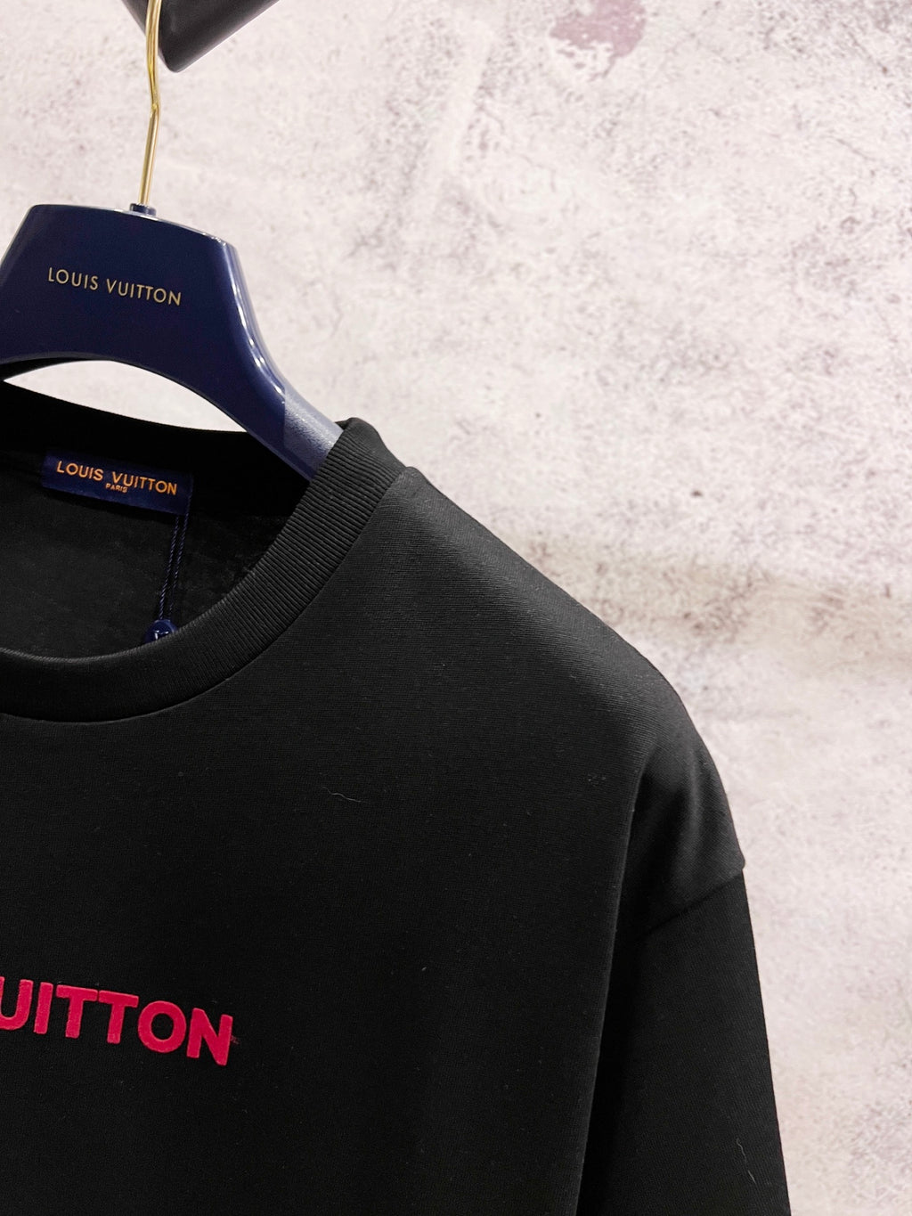 Black short-sleeve T-shirt on hanger with partial red Louis Vuitton logo