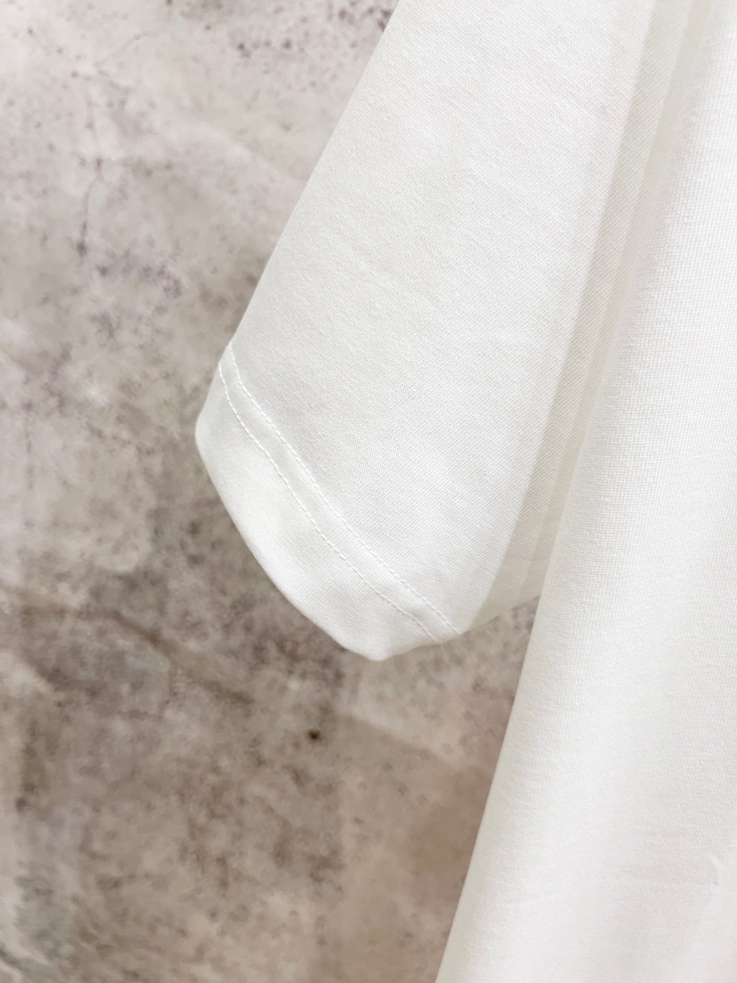 White T-shirt sleeve and shoulder seam detail.