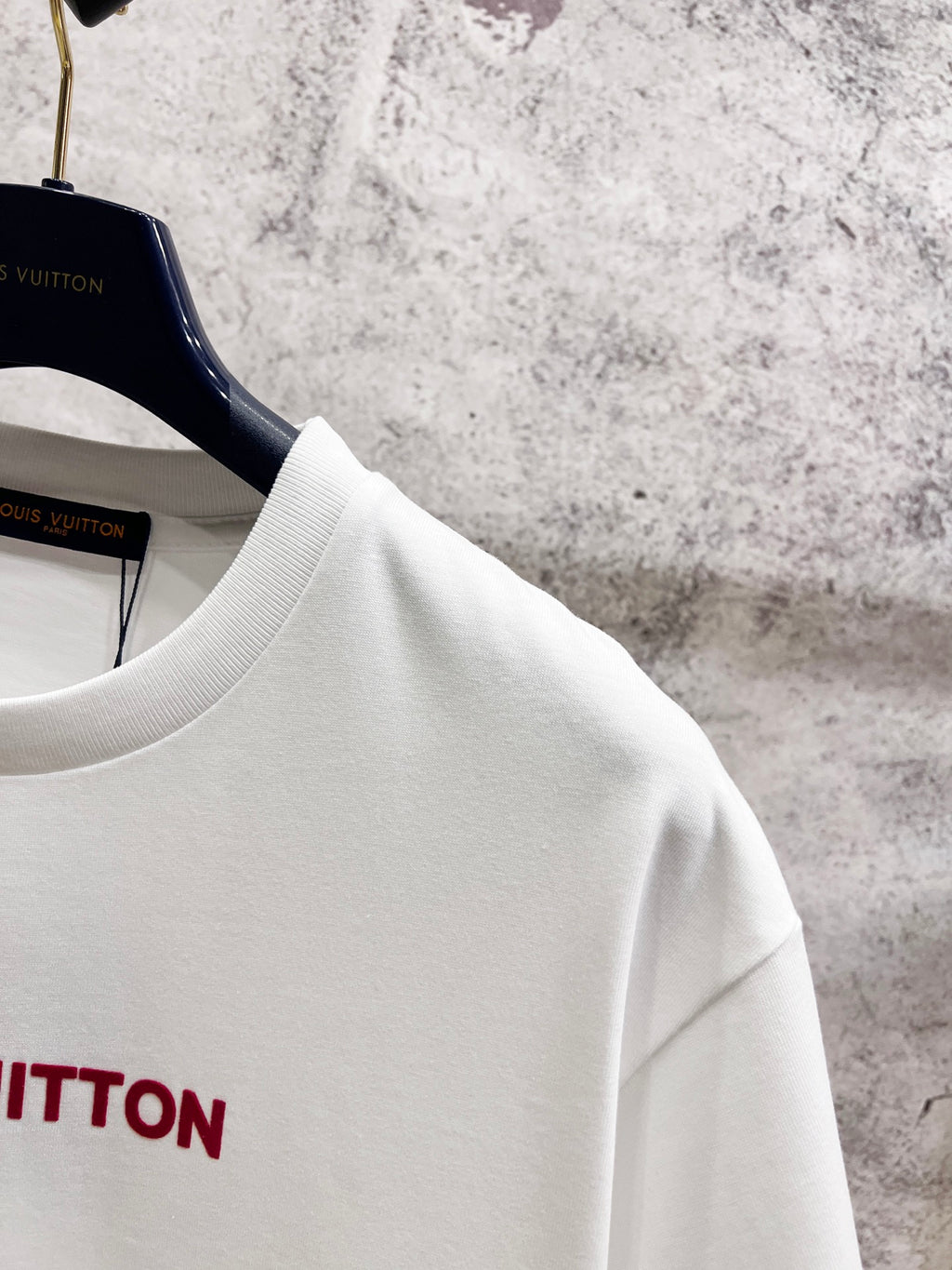 White crewneck short-sleeve T-shirt shoulder and neckline detail on hangers.