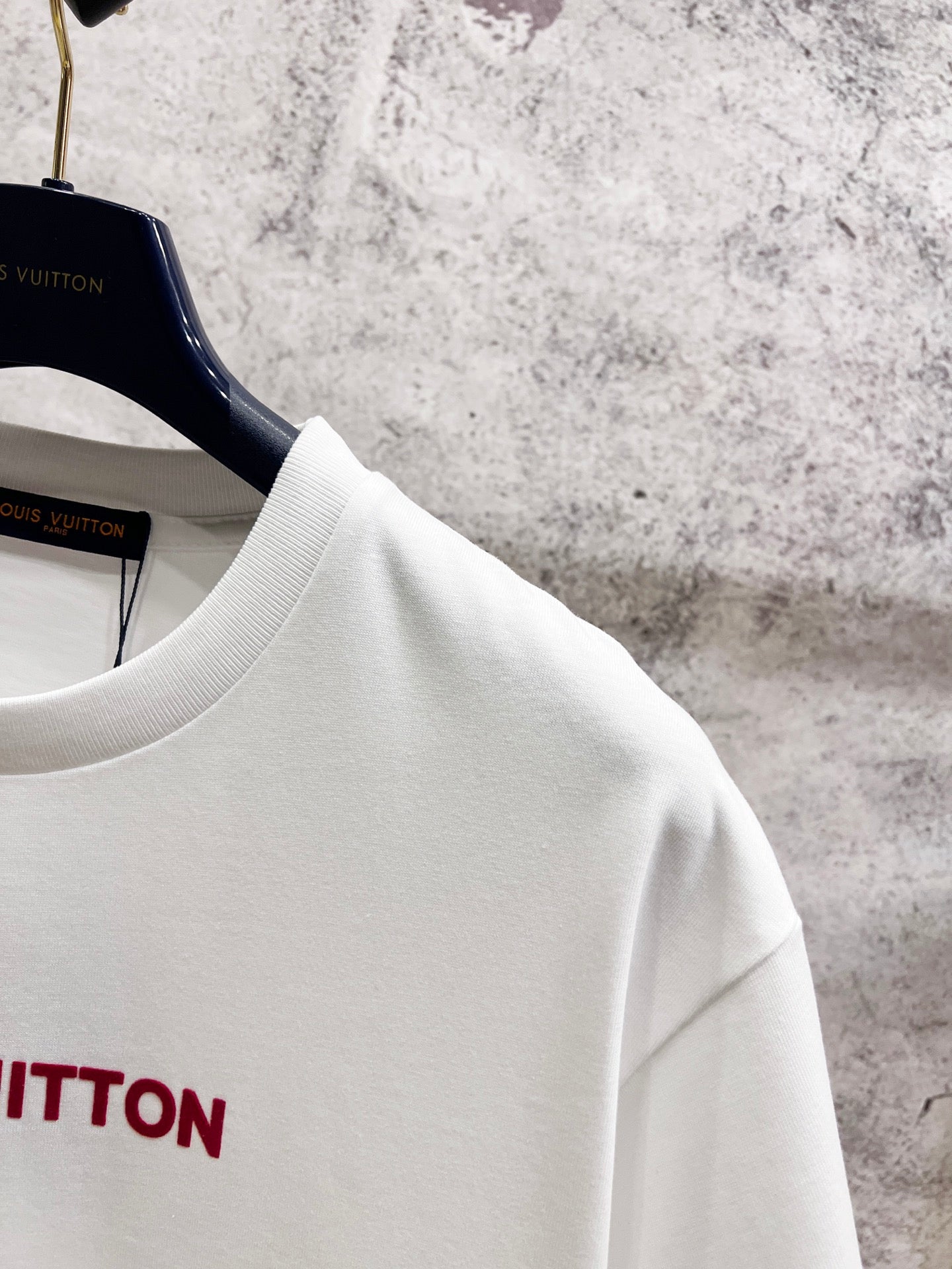 White crewneck short-sleeve T-shirt shoulder and neckline detail on hangers.