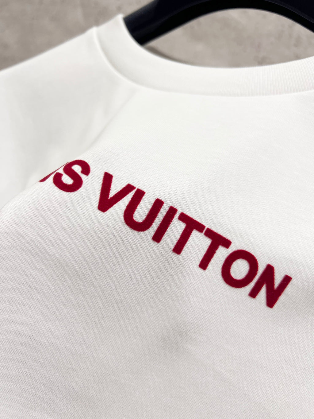 White T-shirt close-up with red Louis Vuitton lettering across the chest.