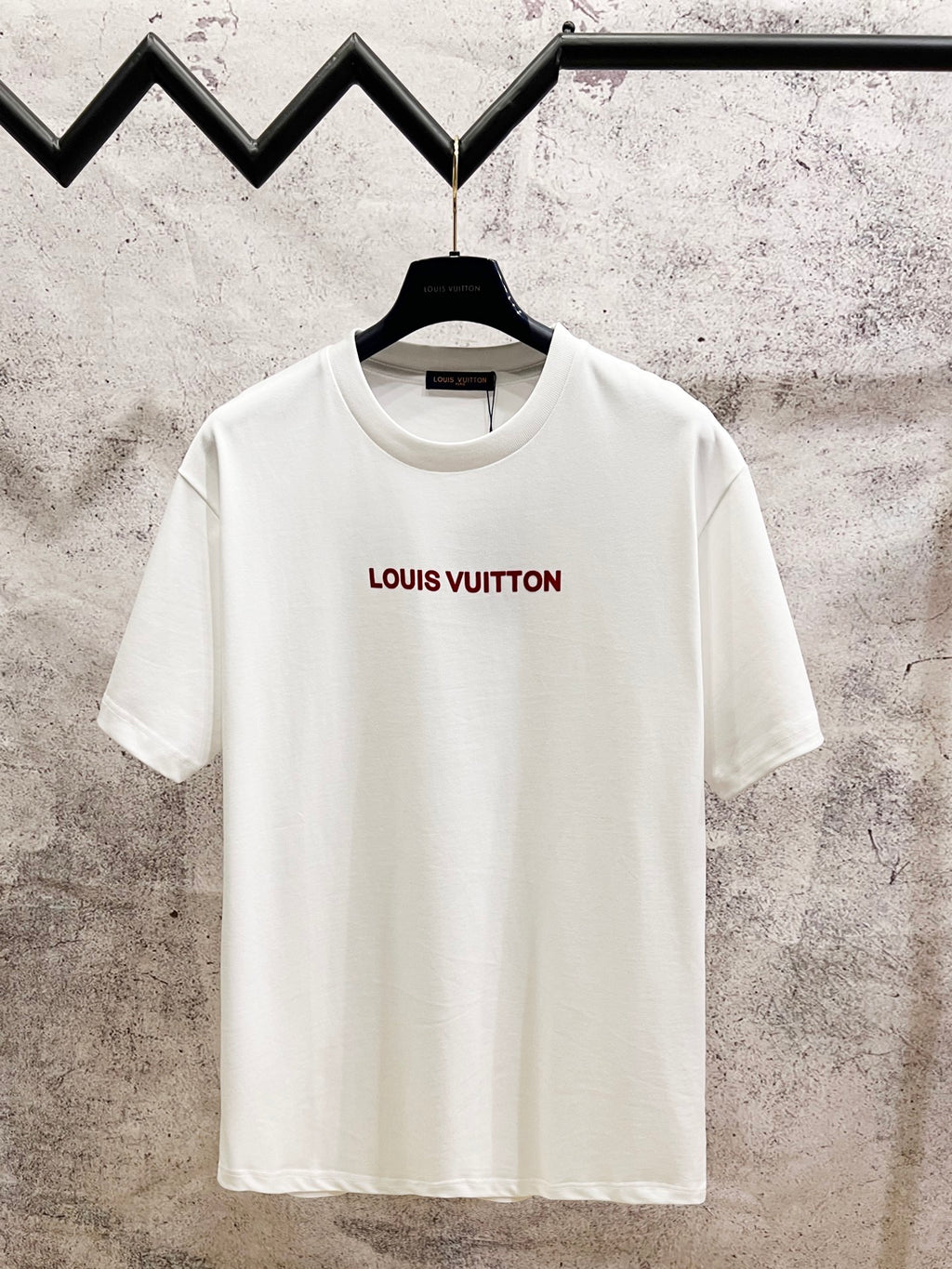 White crewneck short-sleeve T-shirt with red Louis Vuitton logo on chest.
