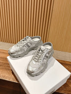 Silver metallic lace-up sneakers on white boxes with textured panels and gray soles