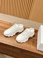 Pair of white Dior lace-up sneakers with sculpted sides and thick rubber sole