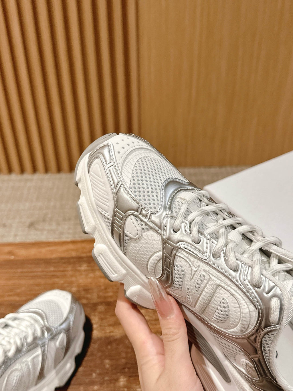 Close-up of a white Dior sneaker upper with embossed details and laces