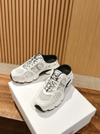 White lace-up sneakers on two white boxes with black trim and logo details