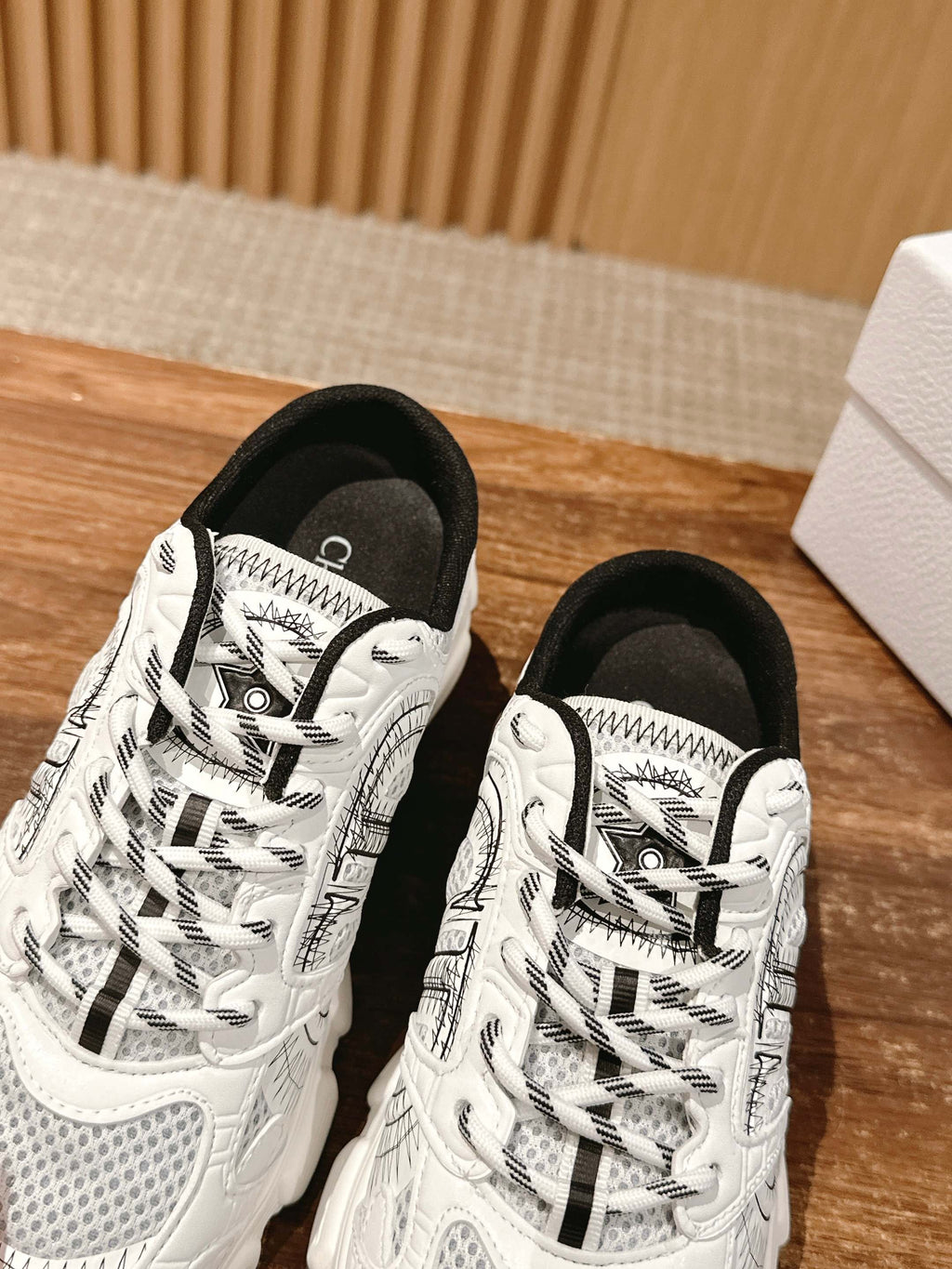 Two white lace-up sneakers with black and gray graphic panels