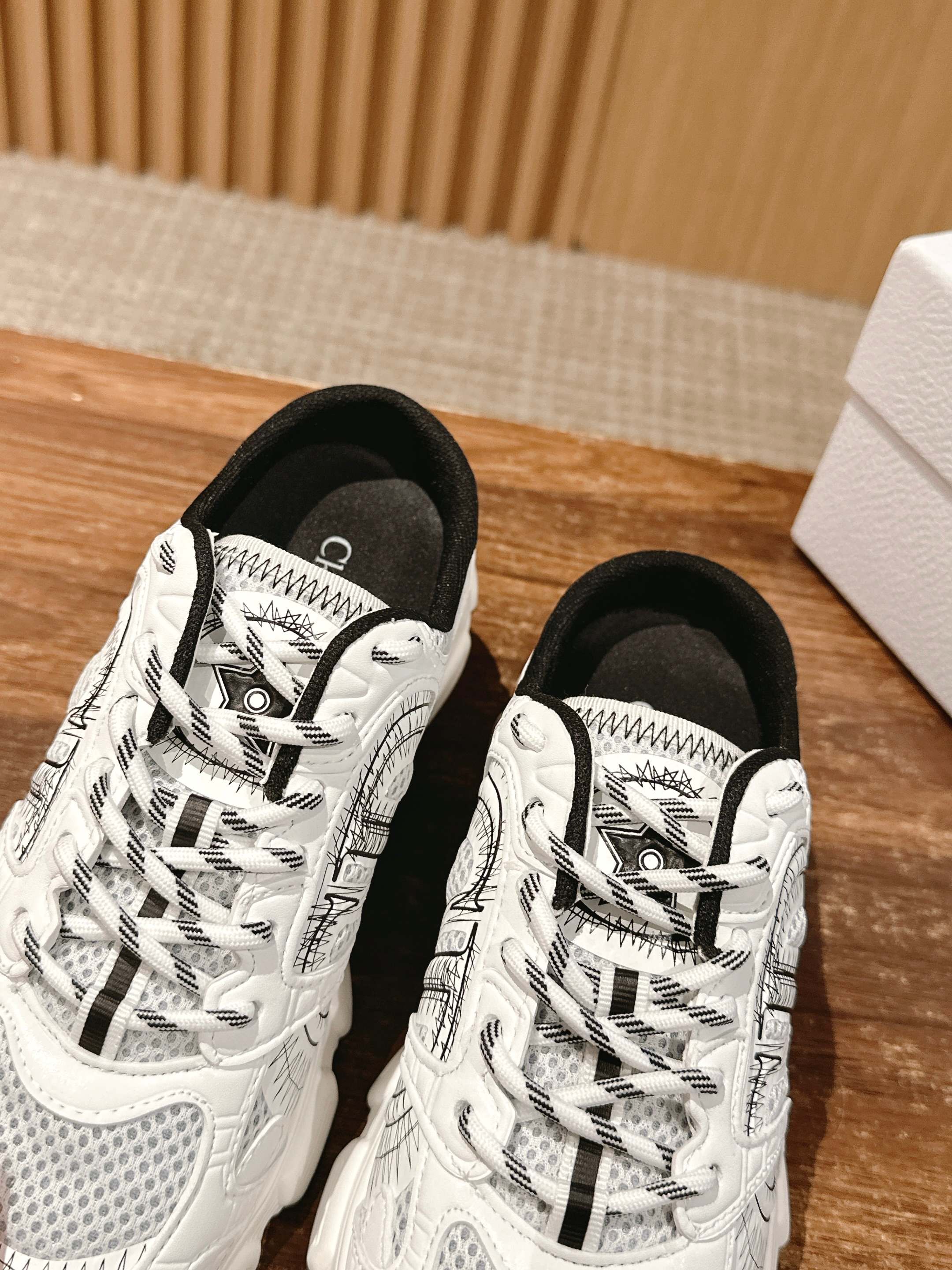 Two white lace-up sneakers with black and gray graphic panels