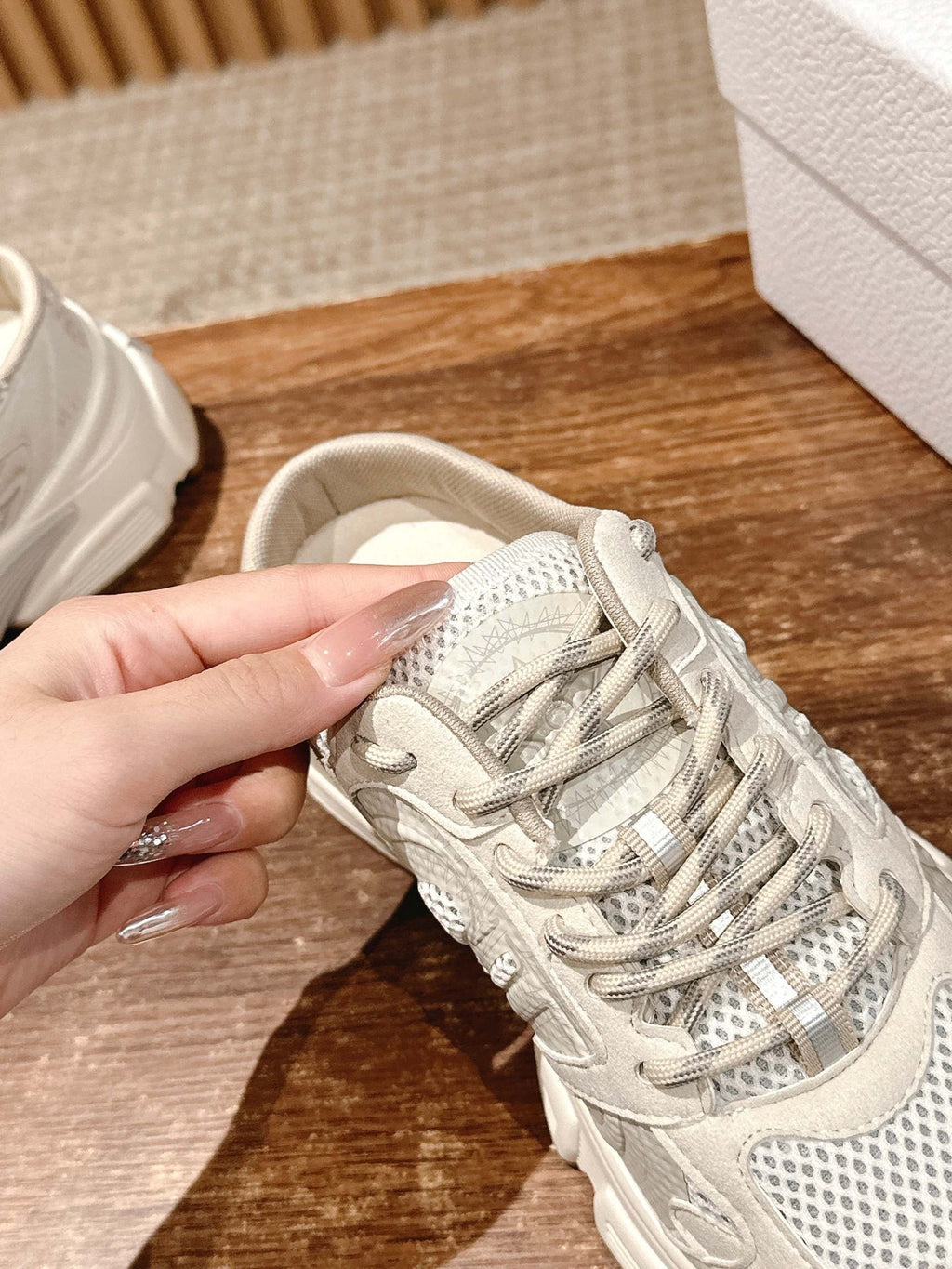 White lace-up sneaker close-up with mesh upper and layered laces